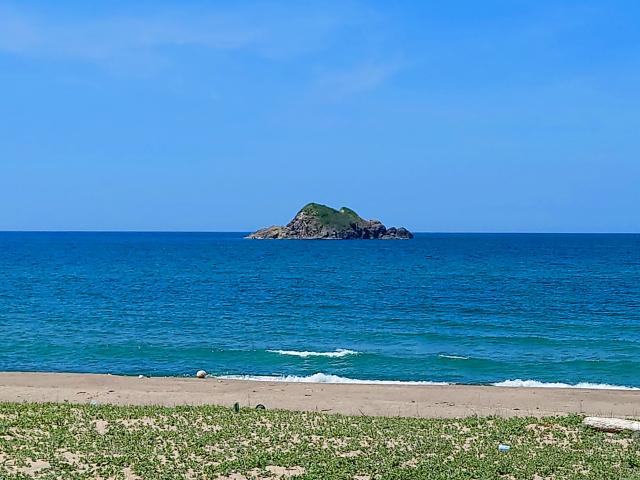 青く澄んだ海の沖に浮かぶ小さな島。穏やかな時間を感じさせる景色です。